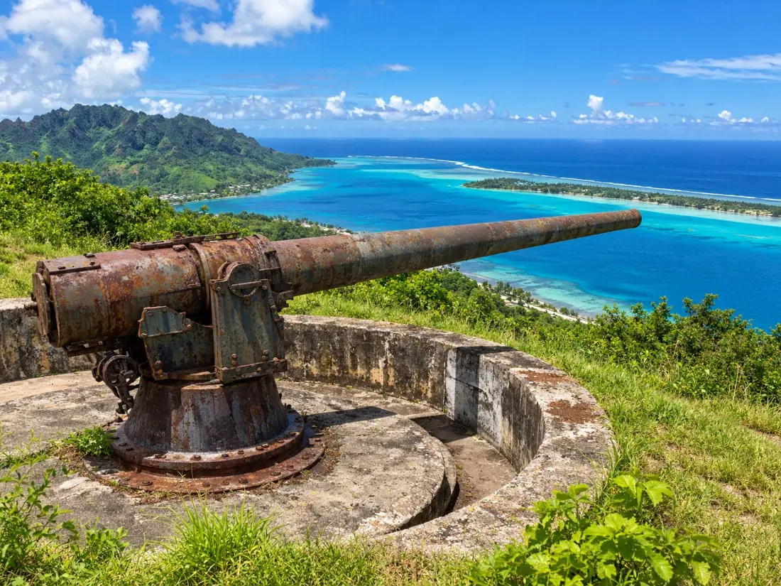 Eine alte Küstenkanone aus dem Zweiten Weltkrieg auf einem grünen Hügel mit Aussichtspunkt über der Bora-Bora-Lagune